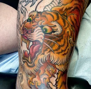 In-progress photo of a snarling Tiger as part of a full leg sleeve tattoo by Mathew Clarke